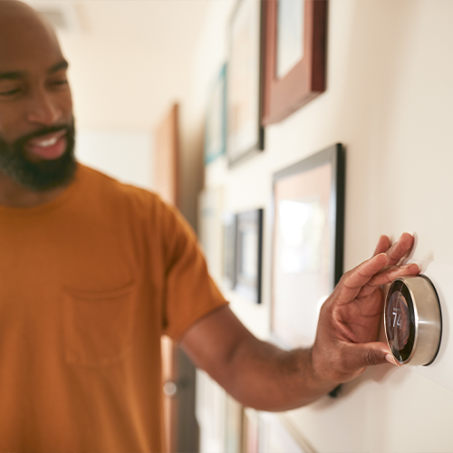 man turning down the thermostat
